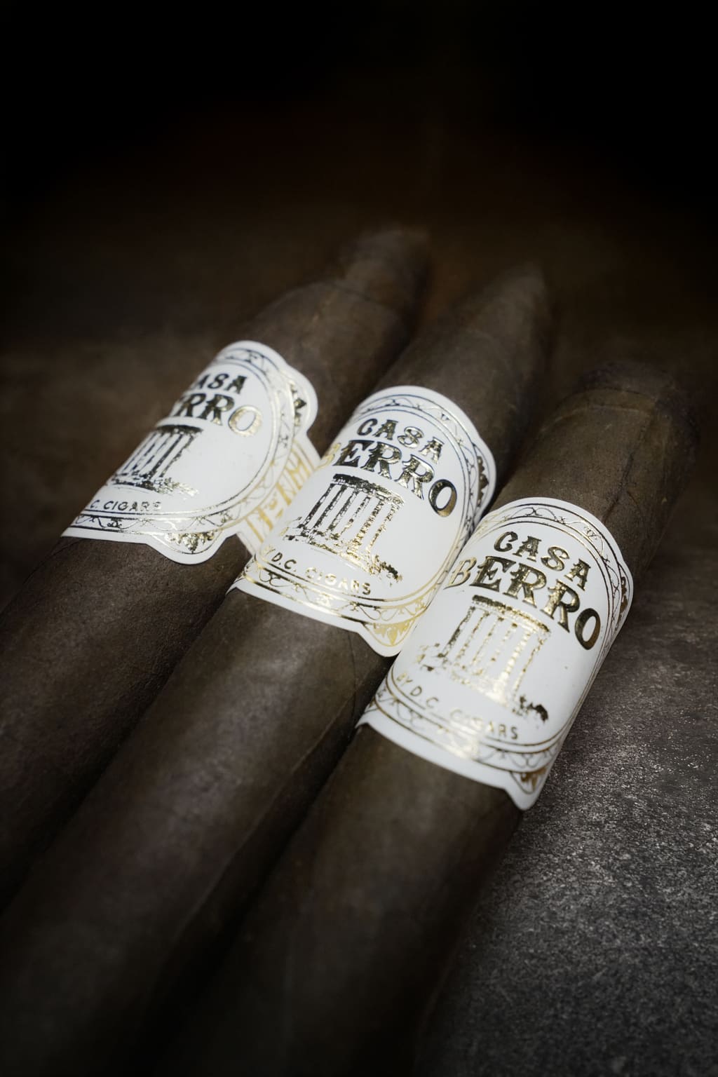 Three Casa Berro White cigars stacked against a warm shadow.