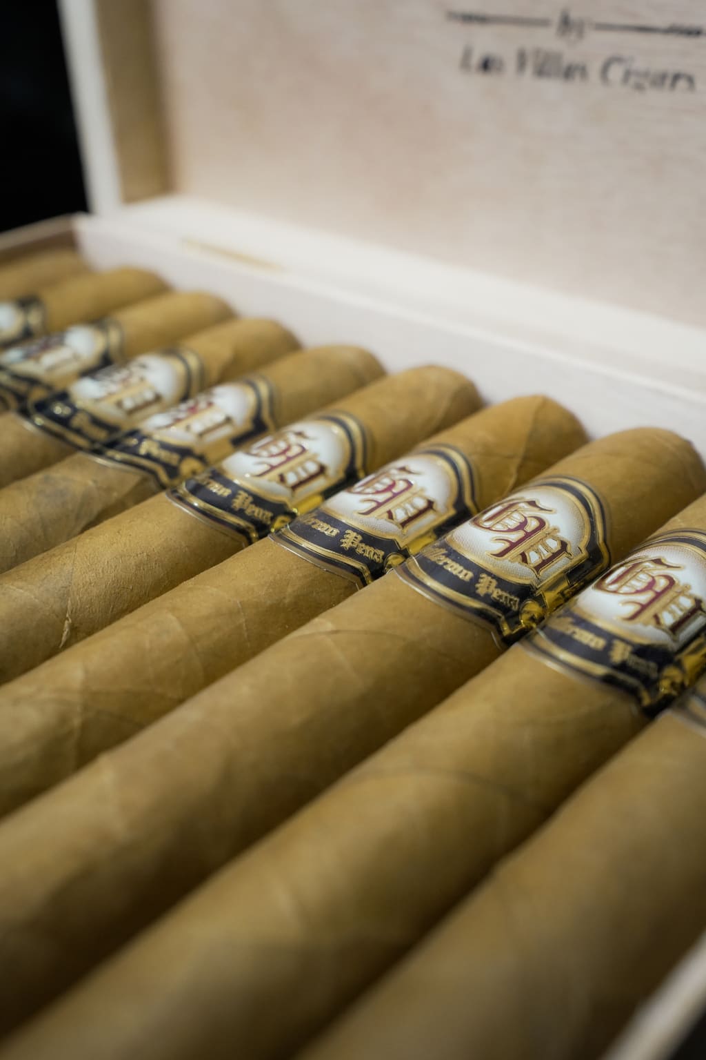 Le Villes Coronas cigars with blue and gold bands, arranged in their open box.